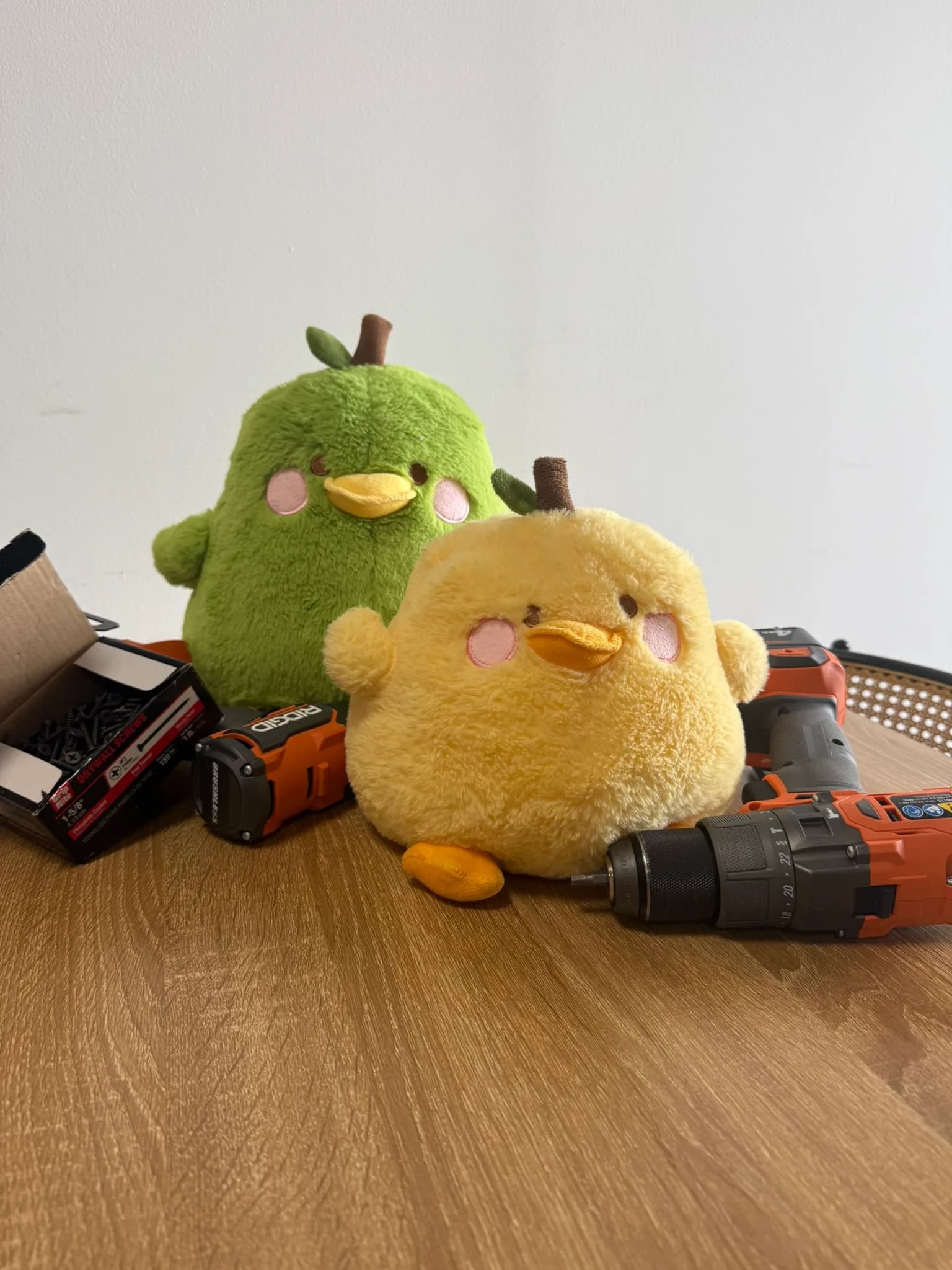 Dougbert and Egbert, green and yellow plush birds, surrounded by drills and screws at a workbench