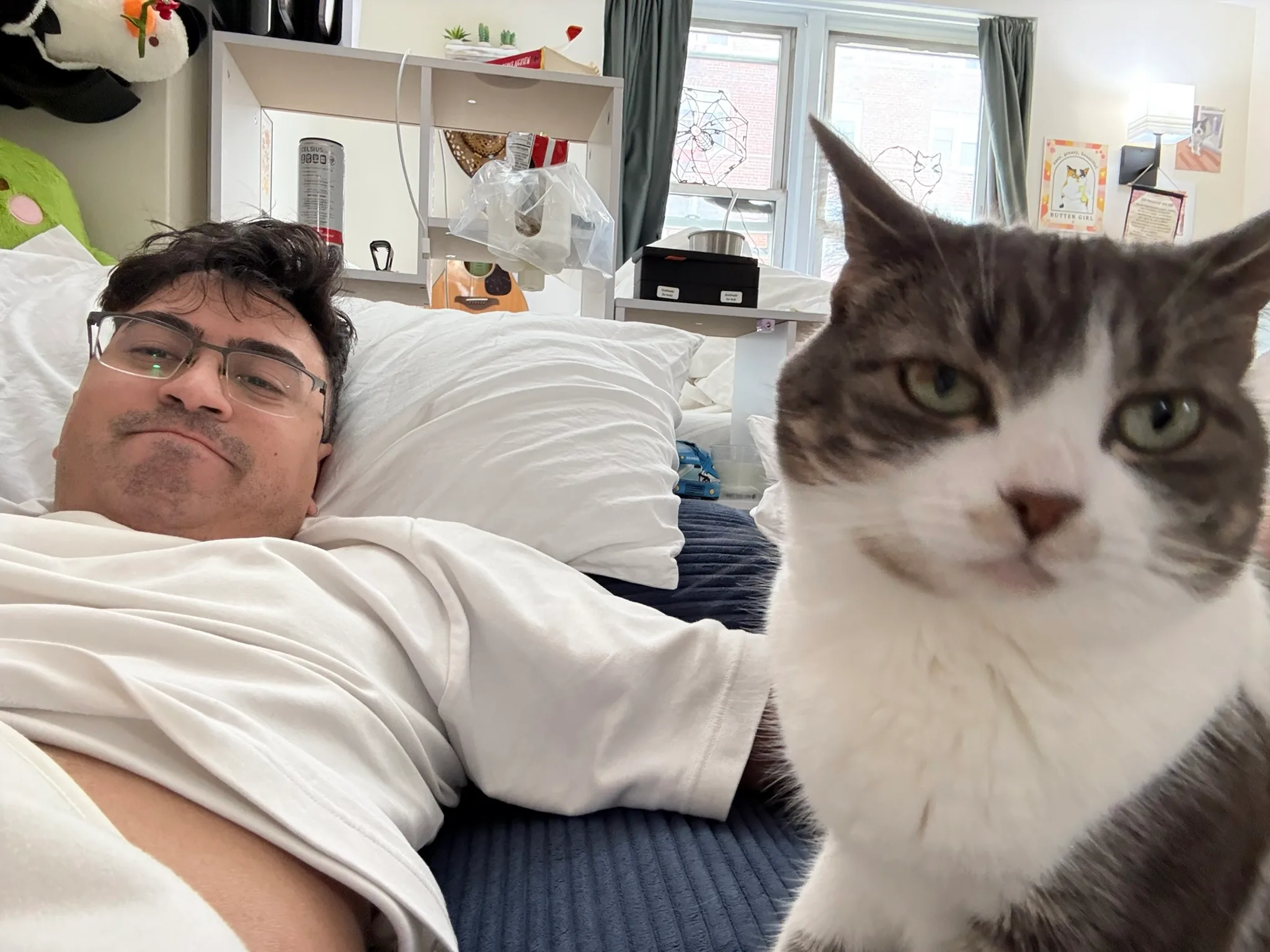 Sen Babu reclining beside a gray-and-white cat in a sunlit studio